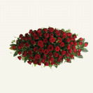 Impressive red rose casket spray cover accompanied with fresh foliage