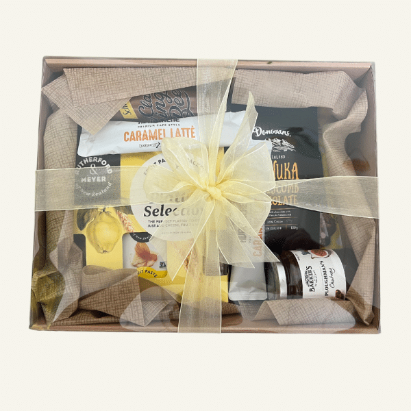 A giftbox including NZ treats chutneys, fruit paste, sparkling ginger beer, crackers, NZ Donovan's chocolates, coffee sachets. All gift wrapped in a box with clear lid & matching bow. Kowhai yellow themed.