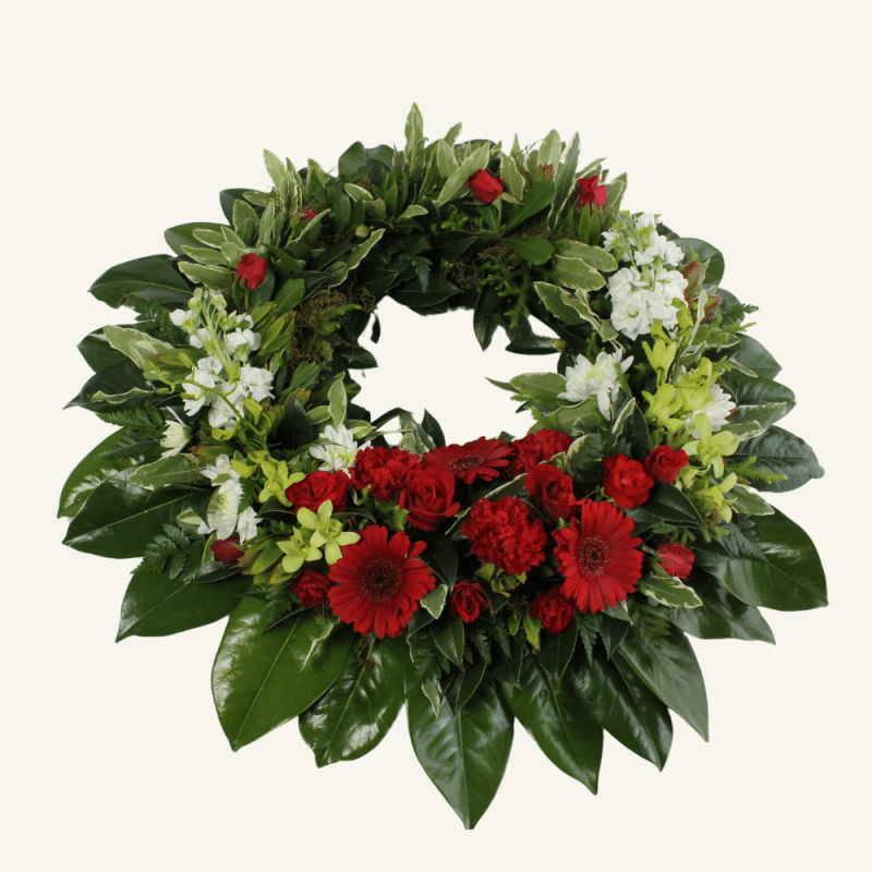 Anzac wreath in traditional reds & greens. Fresh flowers & foliage.